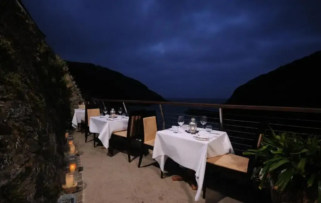 Tables dressées en extérieur avec vue sur la mer au crépuscule.