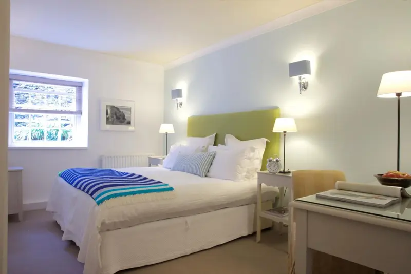 Une chambre lumineuse avec un grand lit recouvert d'une courtepointe bleue et blanche.