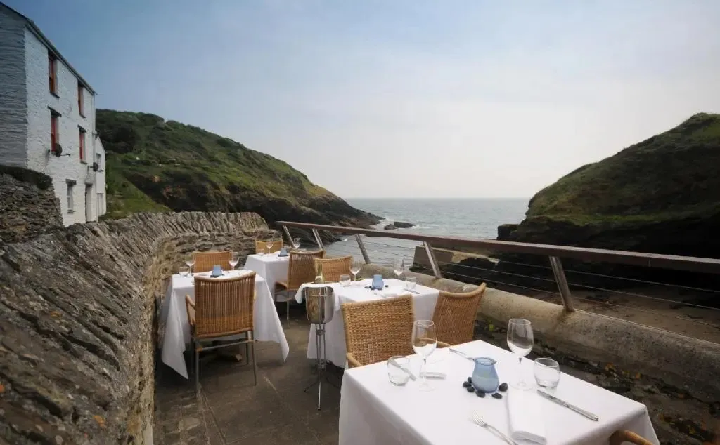 Tables dressées en terrasse avec vue sur la mer et les falaises.