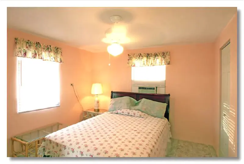 Une chambre lumineuse avec un lit recouvert d'une courtepointe florale et deux fenêtres.
