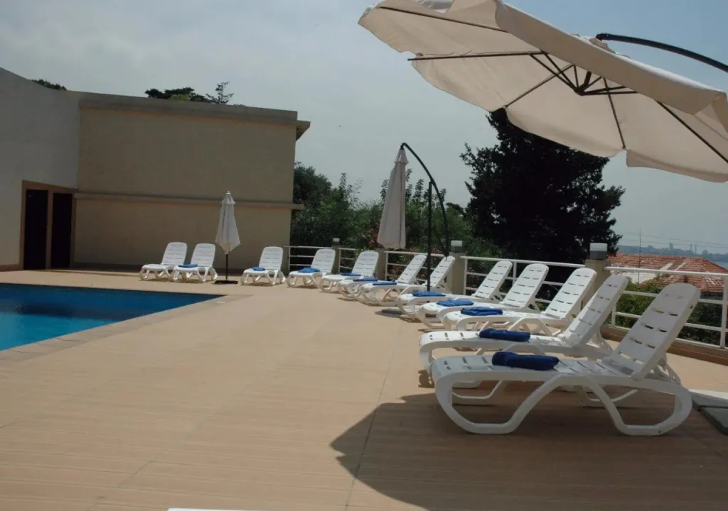 Terrasse avec transats et parasols près d'une piscine.