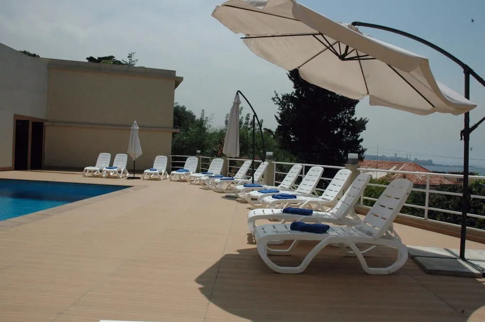 Terrasse avec transats et parasols près d'une piscine.