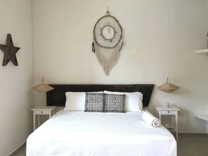 Une chambre lumineuse avec un grand lit recouvert de linge blanc.