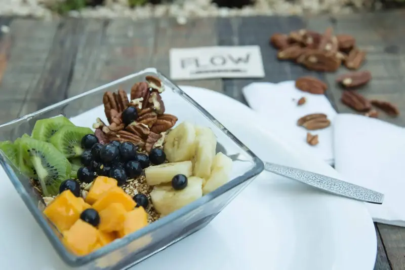 Un bol de fruits frais et de noix est présenté sur une table en bois.