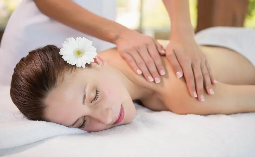 Une femme allongée reçoit un massage du dos dans un cadre relaxant.