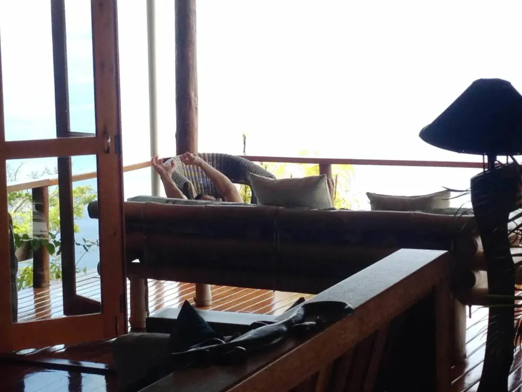 Une personne se repose sur un canapé en bambou avec vue sur la mer.