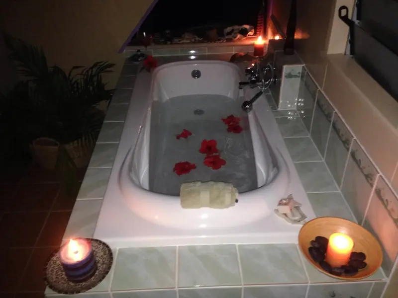 Une baignoire remplie d'eau est décorée de fleurs et illuminée par des bougies.