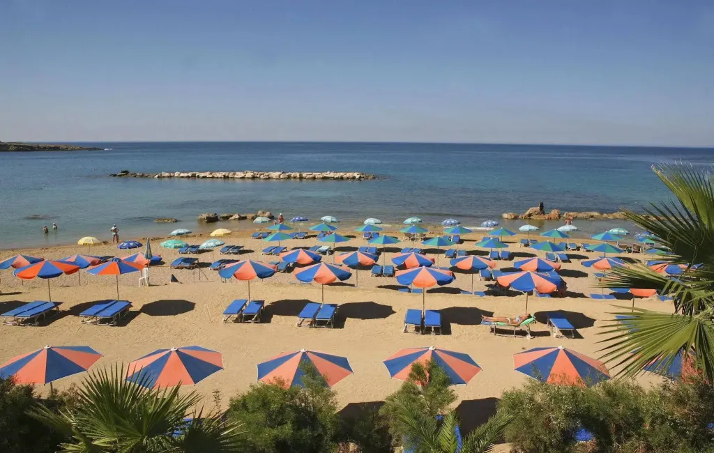 Une plage de sable avec des transats et des parasols colorés face à la mer.
