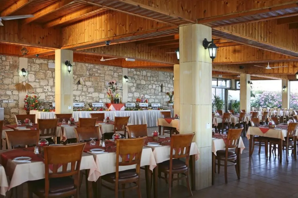 Une salle de restaurant lumineuse avec des tables nappées et un buffet garni.