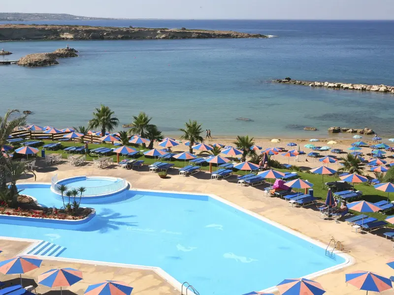 Vue aérienne d'une piscine et d'une plage ensoleillées.
