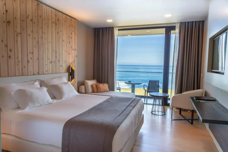 Une chambre lumineuse avec un grand lit donnant sur la mer.