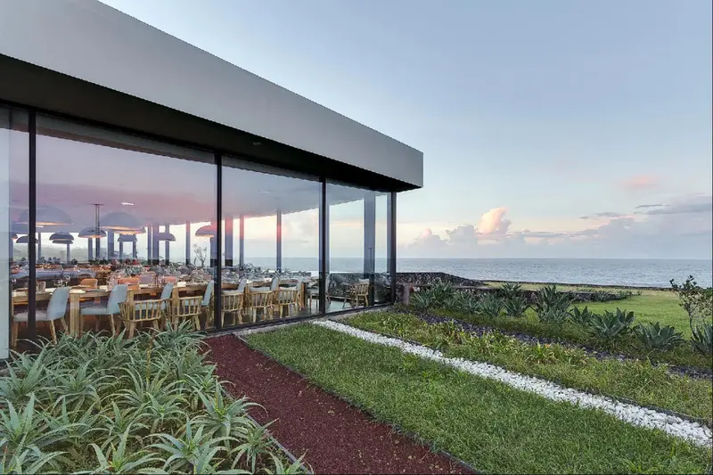 Une salle à manger lumineuse donne sur une pelouse verdoyante et la mer.