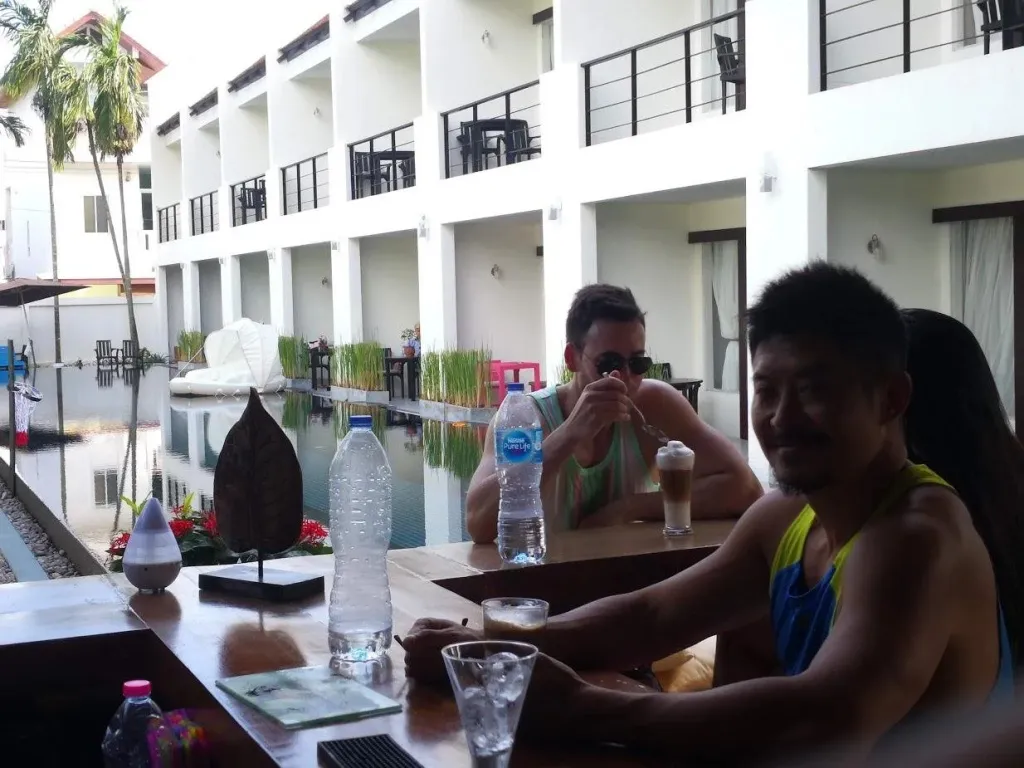 Des clients sont assis à une table près d'une piscine intérieure.