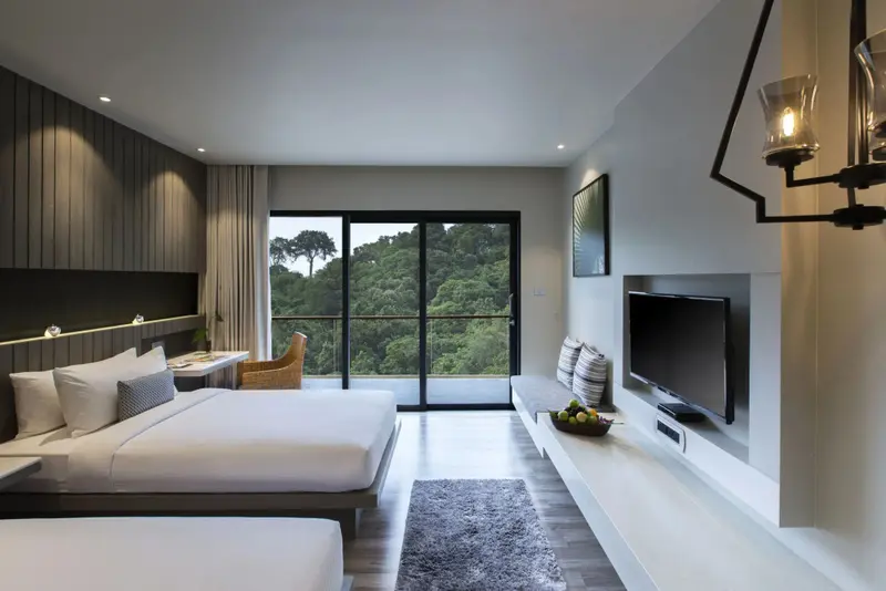 Une chambre lumineuse avec un grand lit et une vue sur la végétation.