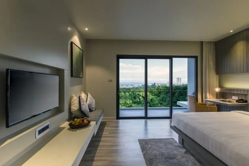 Une chambre lumineuse avec un grand téléviseur et un accès à une terrasse.