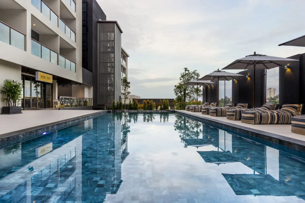 Une piscine rectangulaire bordée de transats sous des parasols.