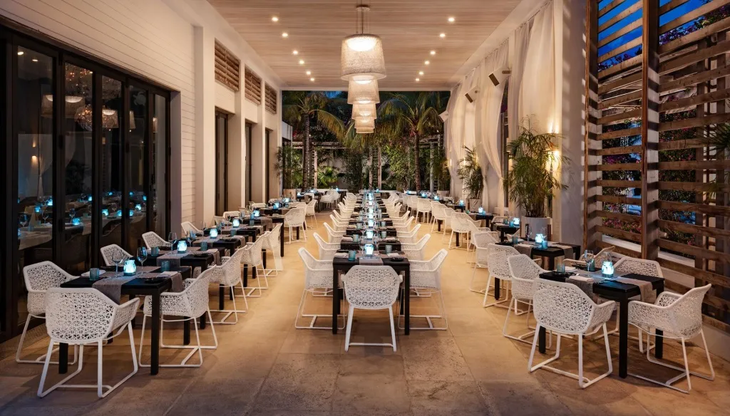 Une salle de restaurant extérieure avec des tables dressées et une décoration lumineuse.