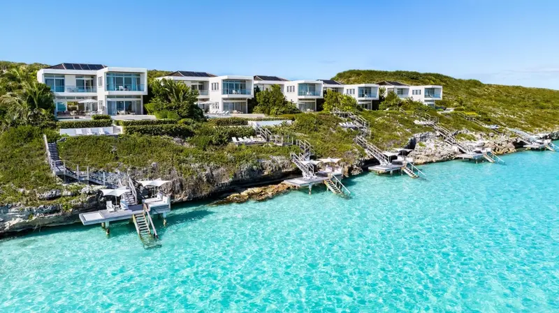Vue aérienne d'un ensemble de villas blanches surplombant une eau turquoise.