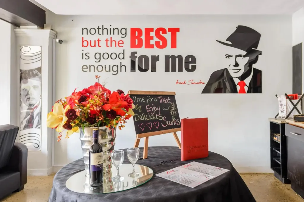 Une table ronde noire est dressée devant un mur décoré avec des portraits et une citation.