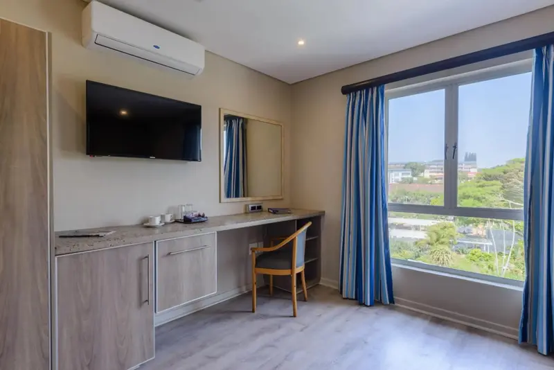 Une chambre lumineuse avec un bureau et une vue sur la végétation.