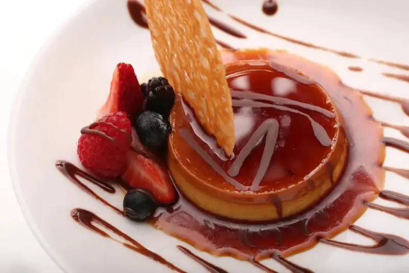 Un dessert crémeux est décoré de fruits frais et d'un biscuit croustillant.