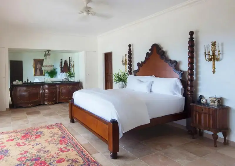 Une chambre lumineuse avec un grand lit à baldaquin et un tapis floral.