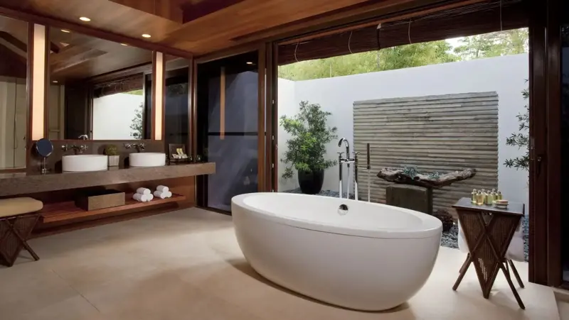 Une salle de bain lumineuse s'ouvre sur une cour intérieure végétalisée.
