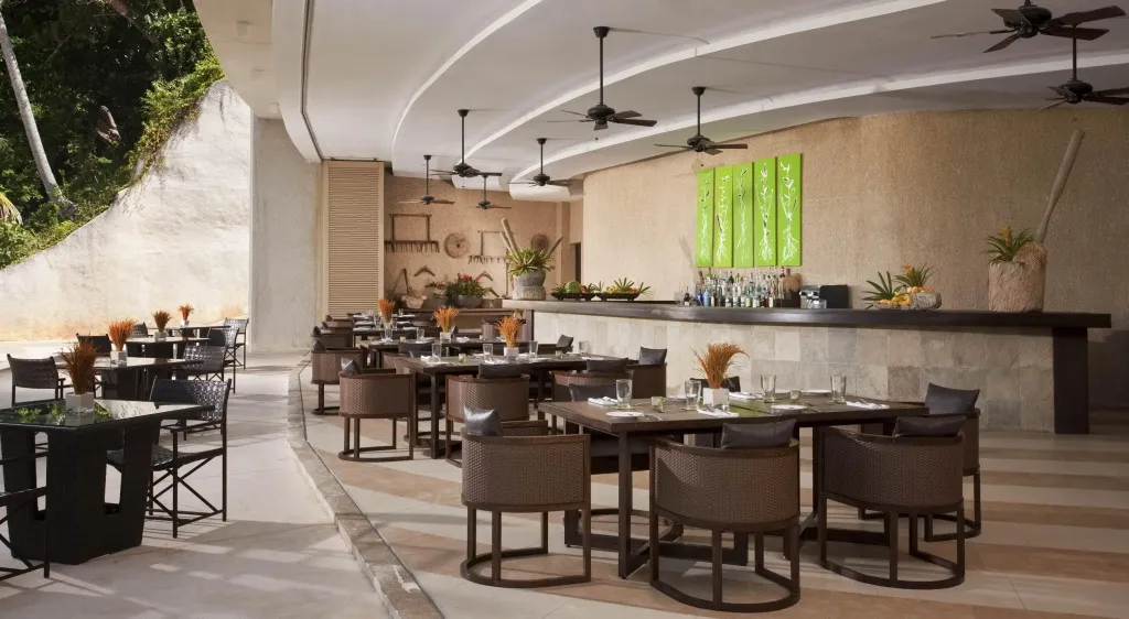 Une salle à manger extérieure avec des tables dressées et un bar.