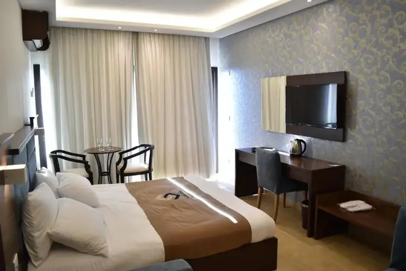 Une chambre lumineuse avec un lit double et un coin salon.