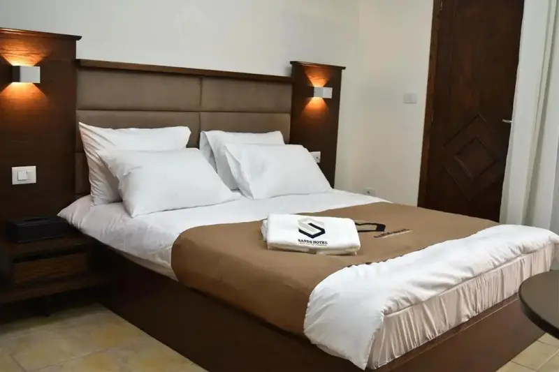 Une chambre avec un grand lit recouvert d'une courtepointe et de coussins blancs.