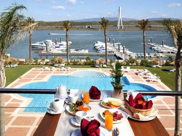 Une table dressée pour le petit-déjeuner surplombe une piscine et un port de plaisance.