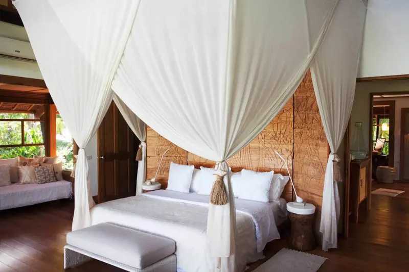 Une chambre lumineuse avec un lit à baldaquin et une décoration en bois sculpté.