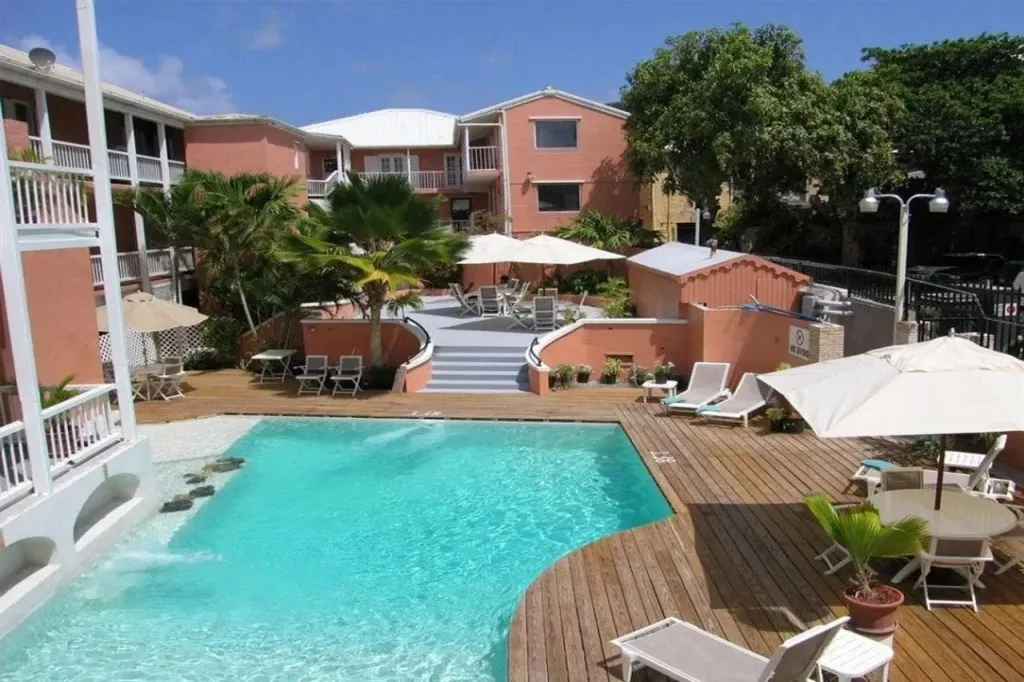 Une piscine turquoise bordée d'une terrasse en bois avec des transats et des parasols.