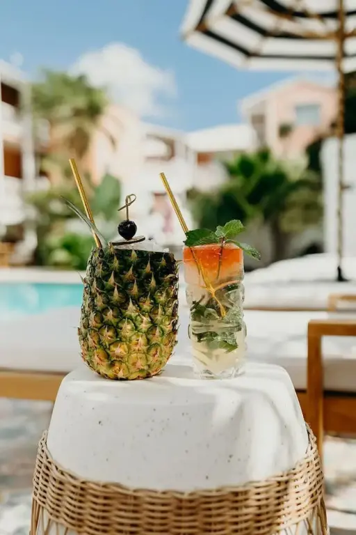 Deux cocktails exotiques présentés sur une table en osier près d'une piscine.