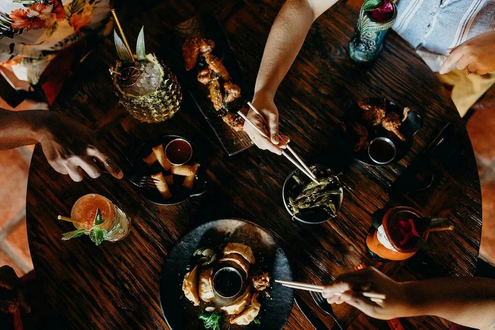 Une table en bois est dressée de plats colorés et de boissons.