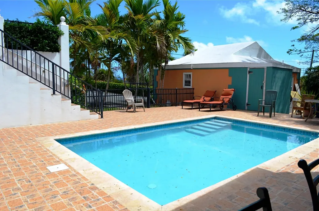 Une piscine rectangulaire bordée d'une terrasse carrelée ensoleillée.
