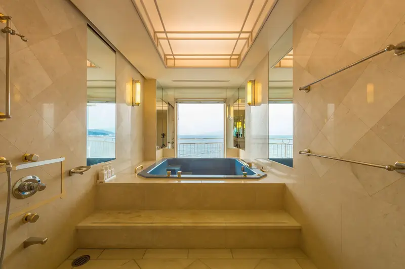 Une grande salle de bain lumineuse avec une baignoire et une vue sur la mer.