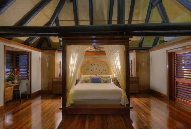 Une chambre spacieuse avec un lit à baldaquin et un parquet en bois.