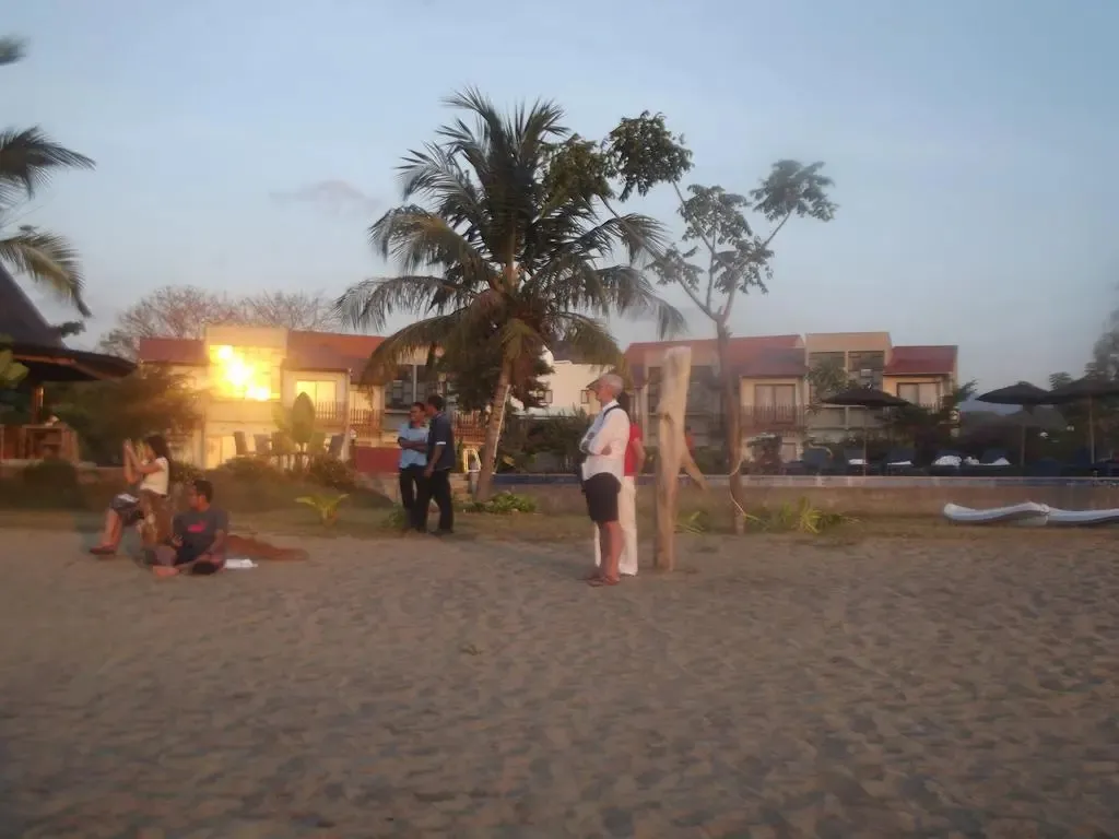Une plage de sable avec des personnes et des bâtiments en arrière-plan.