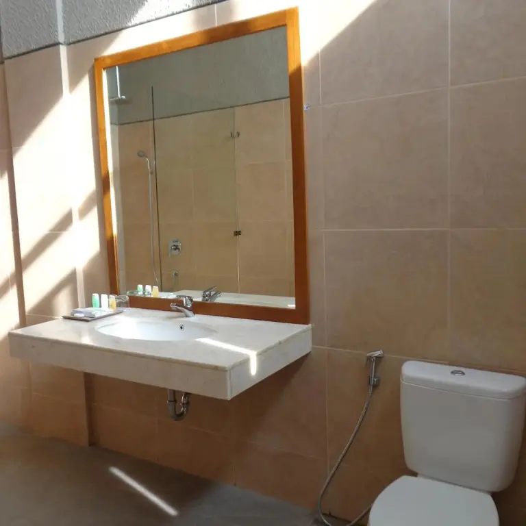 Une salle de bain lumineuse avec un grand miroir et un lavabo.