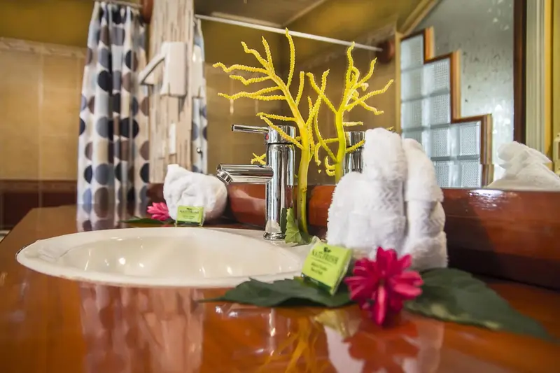 Un lavabo avec des serviettes et des fleurs sur un meuble en bois.