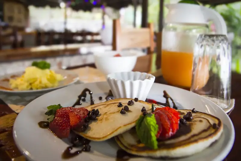 Assiette de crêpes garnies de fruits frais et de chocolat, accompagnées d'un jus d'orange.
