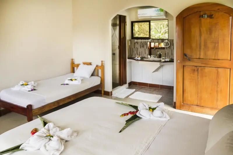 Une chambre lumineuse avec deux lits décorés de fleurs et une kitchenette.