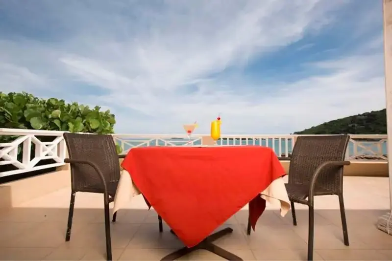 Table dressée sur une terrasse avec vue sur la mer et la végétation.