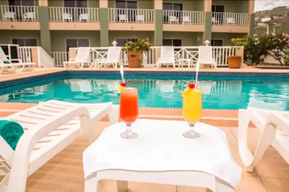 Deux cocktails colorés reposent sur une table basse près d'une piscine ensoleillée.