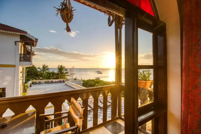 Vue sur la mer au coucher du soleil depuis un balcon fleuri.