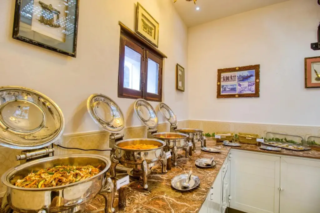 Un buffet propose une variété de plats chauds dans une salle lumineuse.