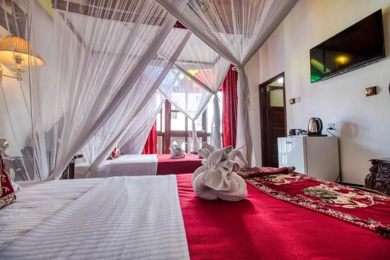 Une chambre avec lits à baldaquin et décoration soignée.