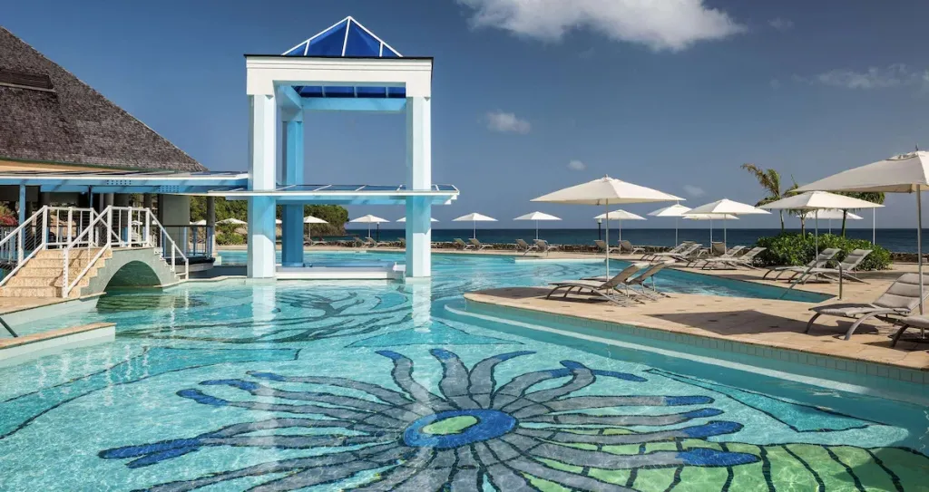 Une piscine à débordement avec un bar intégré et des transats en bord de mer.