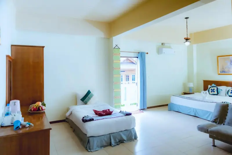 Une chambre lumineuse avec deux lits simples et une vue sur l'extérieur.